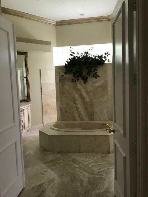 bathroom featuring a relaxing tiled bath, crown molding, tile flooring, and vanity