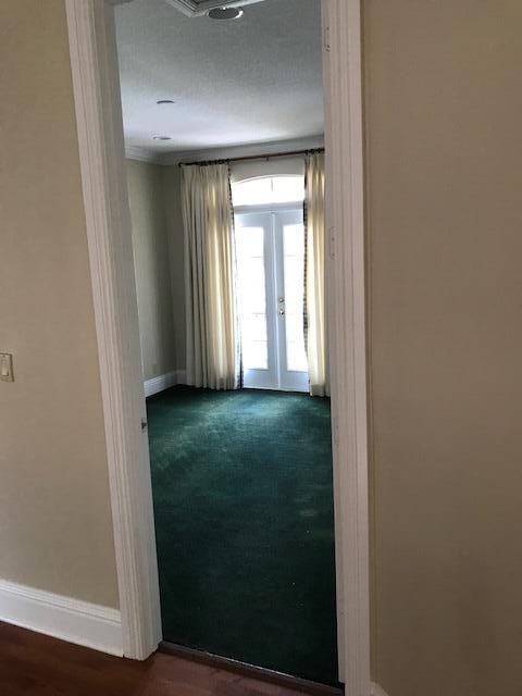 empty room featuring french doors, dark carpet, and a textured ceiling