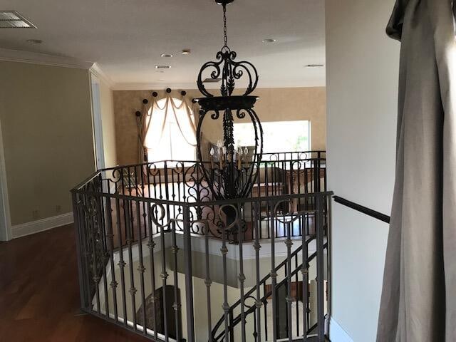 stairs featuring a chandelier, hardwood / wood-style flooring, and crown molding