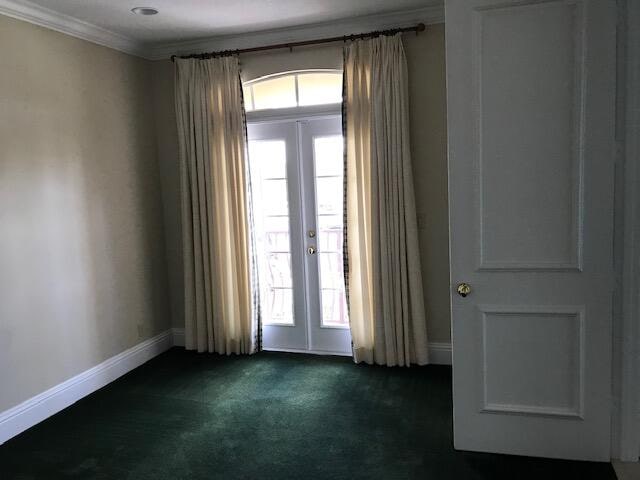 unfurnished room featuring french doors, dark carpet, and ornamental molding