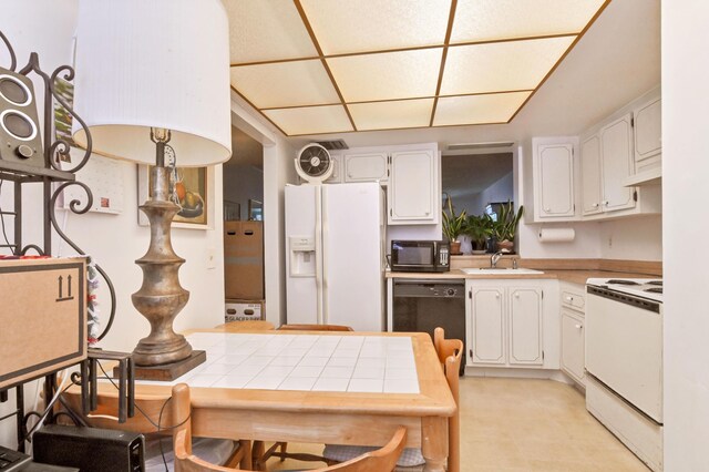 kitchen featuring tile counters, white cabinetry, a sink, and black appliances