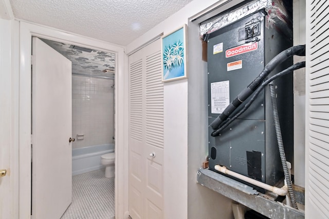 bathroom with a textured ceiling, tiled shower / bath combo, toilet, and tile patterned floors