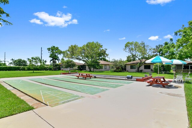 view of property's community featuring shuffleboard and a yard