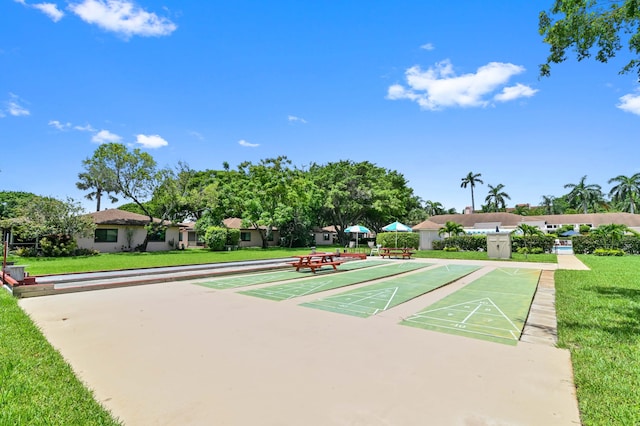 view of community with shuffleboard and a yard