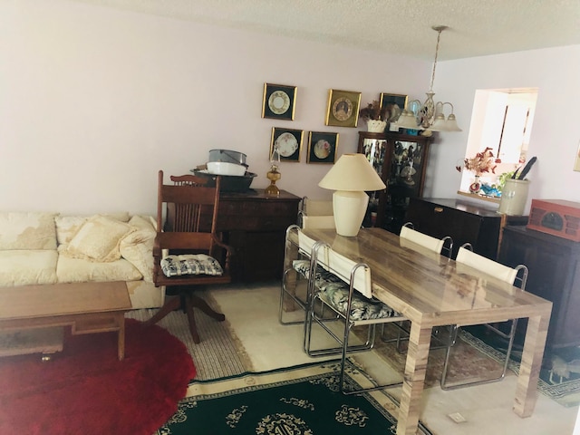 dining room featuring an inviting chandelier, a textured ceiling, and carpet floors