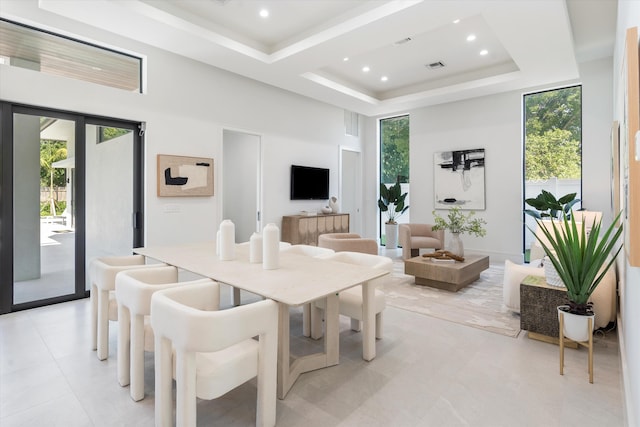 dining space featuring a tray ceiling, a towering ceiling, and a healthy amount of sunlight