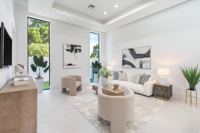 tiled living room with plenty of natural light and a raised ceiling