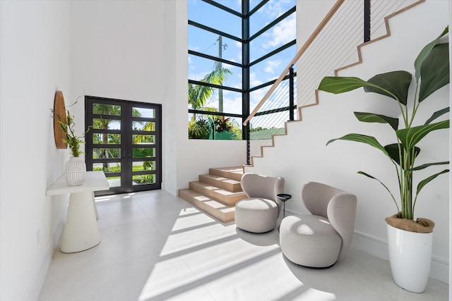 staircase featuring french doors, a towering ceiling, and a healthy amount of sunlight