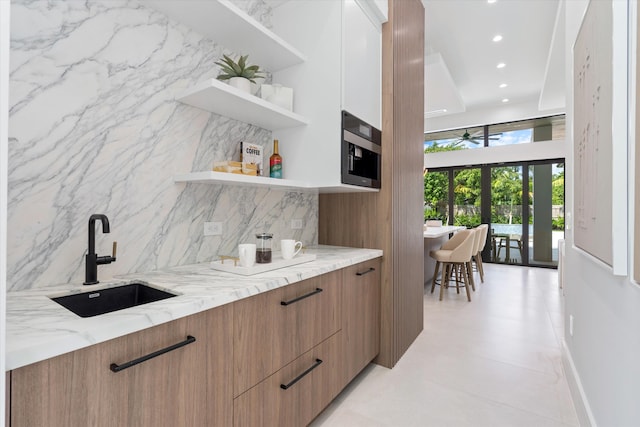 bar featuring light stone countertops, french doors, tasteful backsplash, and sink