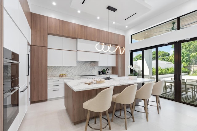 kitchen featuring white cabinetry, tasteful backsplash, decorative light fixtures, light tile patterned floors, and black appliances