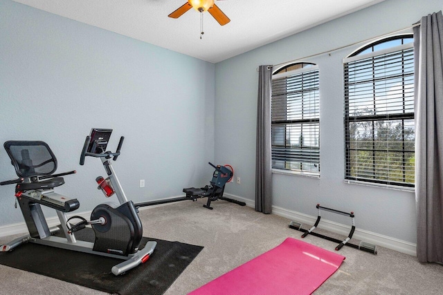 exercise room with ceiling fan and light carpet