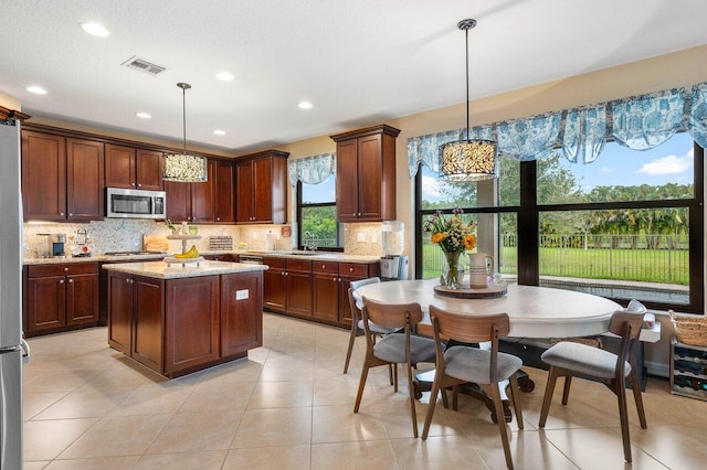 kitchen featuring light stone countertops, decorative light fixtures, stainless steel appliances, and sink