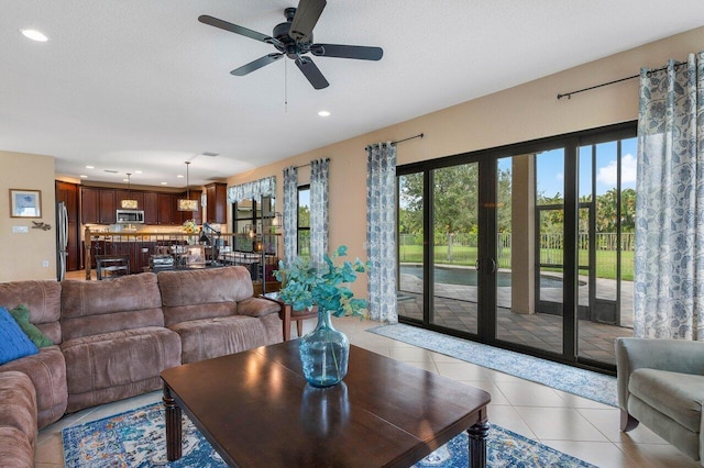 living room with ceiling fan, light tile patterned flooring, and a textured ceiling