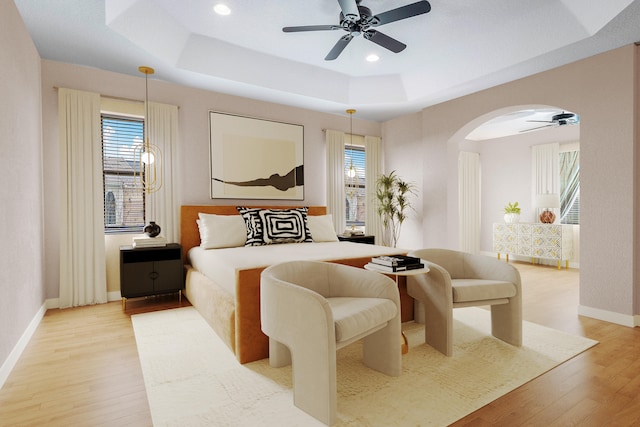 bedroom with hardwood / wood-style floors, a tray ceiling, and ceiling fan