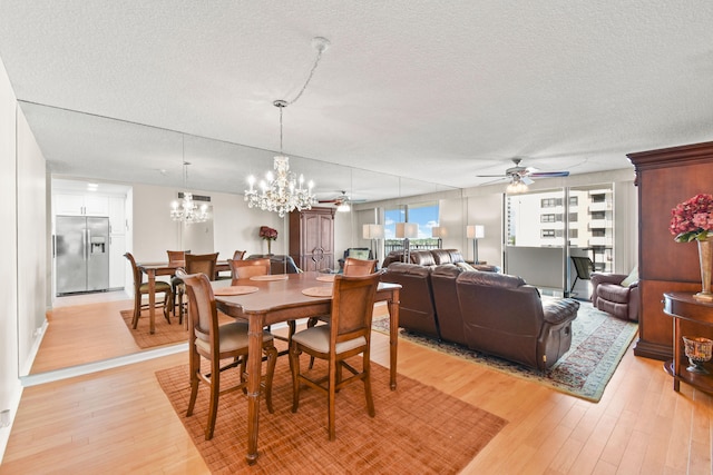 dining room featuring ceiling fan with notable chandelier, light hardwood / wood-style floors, and a textured ceiling