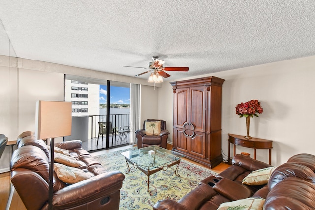 living room with hardwood / wood-style floors, ceiling fan, and a textured ceiling