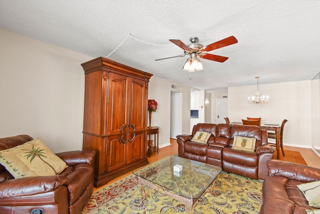 living room with ceiling fan with notable chandelier, hardwood / wood-style flooring, and a textured ceiling