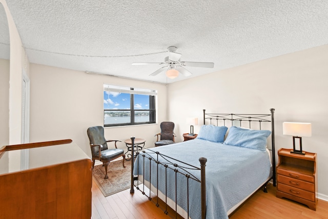 bedroom featuring a textured ceiling, ceiling fan, and light hardwood / wood-style floors