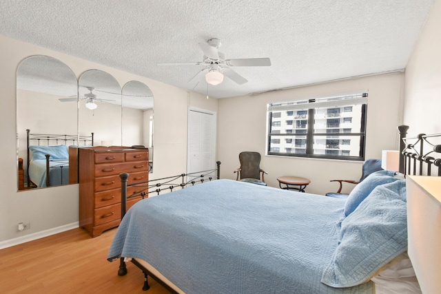 bedroom with a closet, light hardwood / wood-style floors, ceiling fan, and a textured ceiling