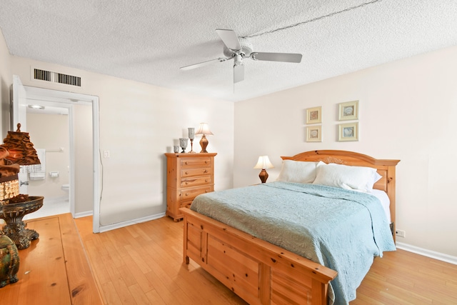 bedroom featuring connected bathroom, light hardwood / wood-style floors, ceiling fan, and a textured ceiling