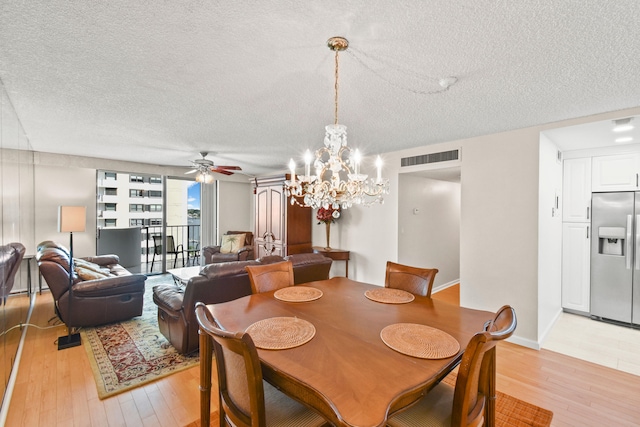 tiled dining area with ceiling fan with notable chandelier and a textured ceiling