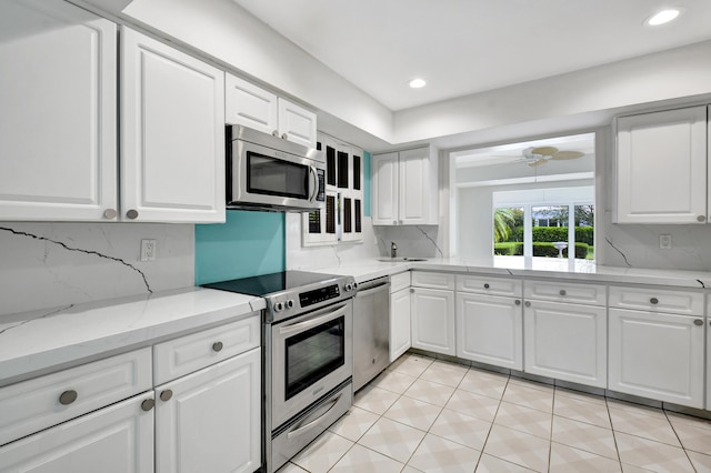 kitchen with white cabinetry, backsplash, stainless steel appliances, light tile floors, and ceiling fan