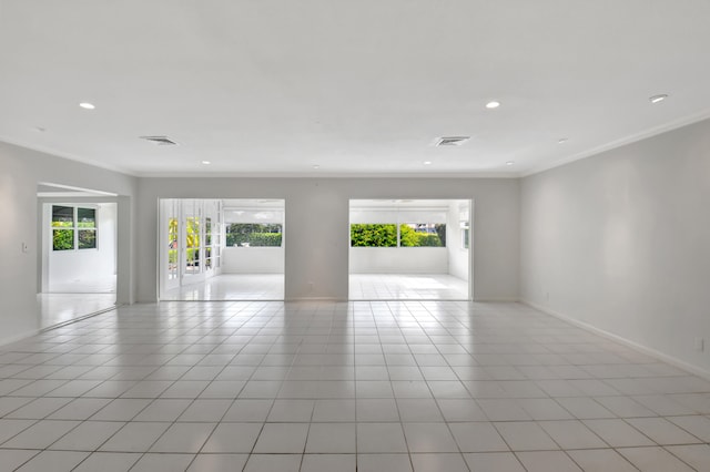 empty room with a wealth of natural light, ornamental molding, and light tile floors