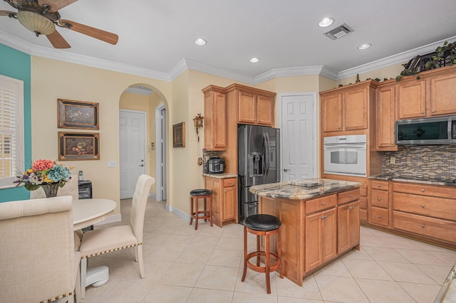 dining space with crown molding, light tile patterned floors, and ceiling fan