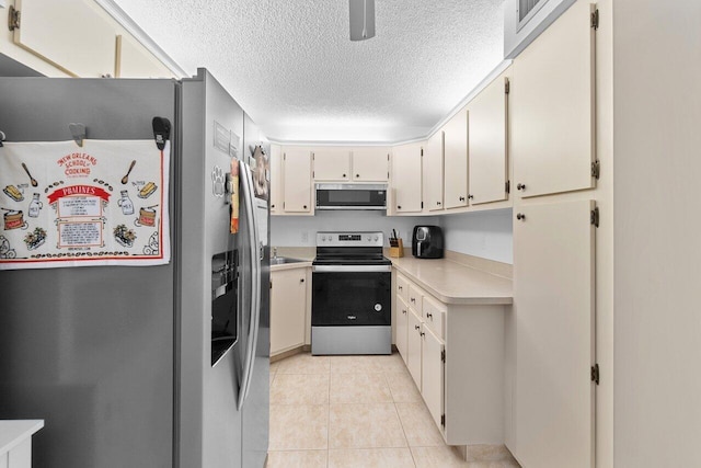 kitchen with stainless steel appliances, light tile floors, and a textured ceiling