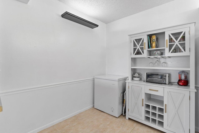 laundry area featuring a textured ceiling and light tile floors