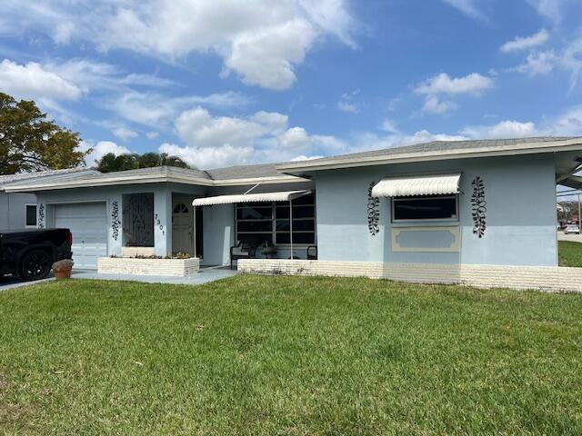 back of property featuring a garage and a lawn