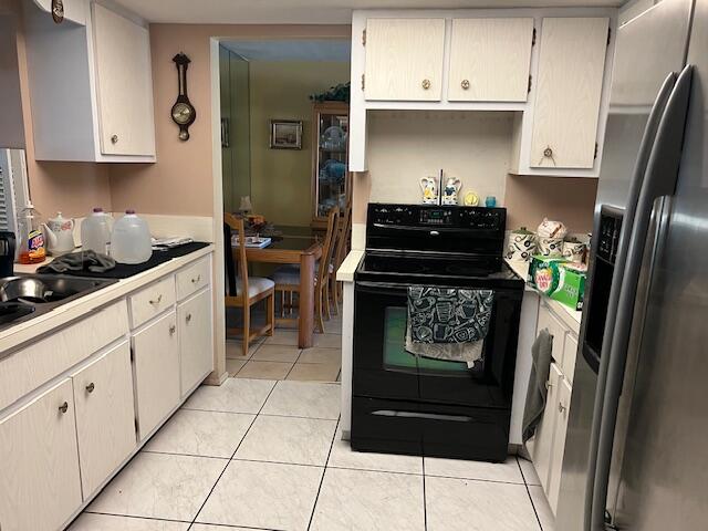 kitchen with electric range, stainless steel refrigerator with ice dispenser, sink, and light tile floors