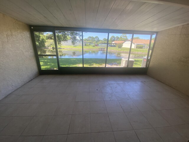 unfurnished sunroom with a water view and wooden ceiling