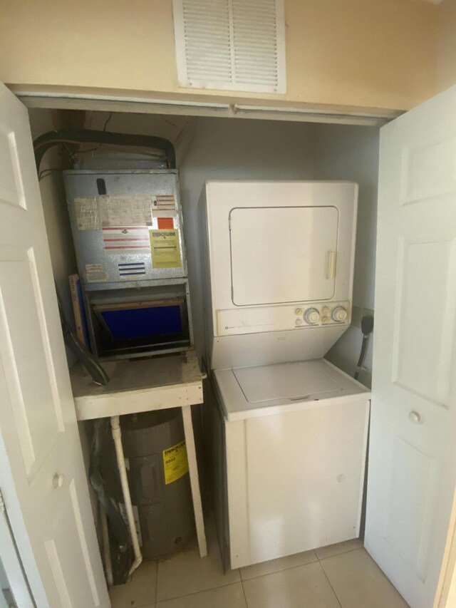 laundry area featuring light tile patterned flooring and stacked washer and clothes dryer