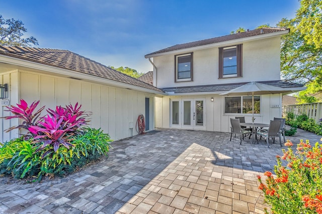 rear view of property with a patio area, fence, outdoor dining area, and french doors