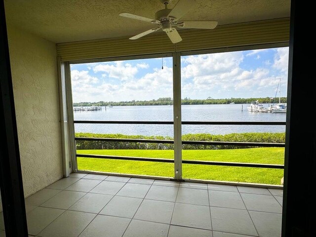 unfurnished sunroom featuring a ceiling fan and a water view