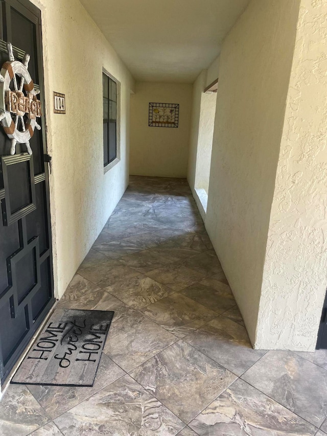 hallway featuring stone finish flooring and a textured wall