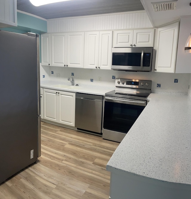 kitchen with a sink, visible vents, white cabinets, light countertops, and appliances with stainless steel finishes