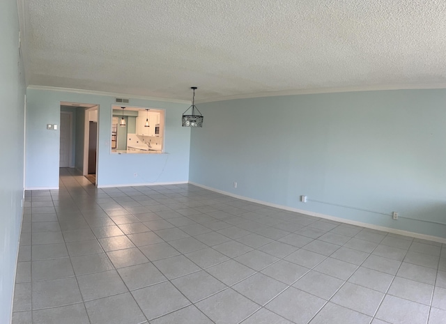 spare room with light tile patterned floors, visible vents, baseboards, ornamental molding, and a textured ceiling