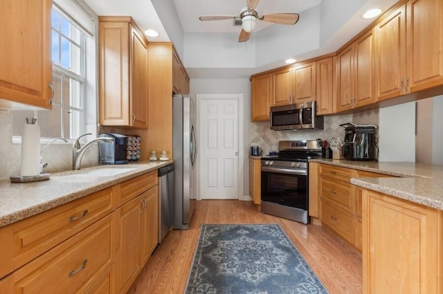 kitchen featuring appliances with stainless steel finishes, tasteful backsplash, ceiling fan, and light hardwood / wood-style flooring