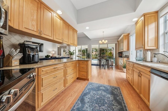 kitchen with backsplash, light wood-type flooring, a chandelier, stainless steel appliances, and kitchen peninsula