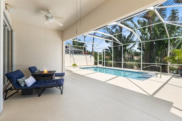 view of pool with a fire pit, a lanai, ceiling fan, and a patio area