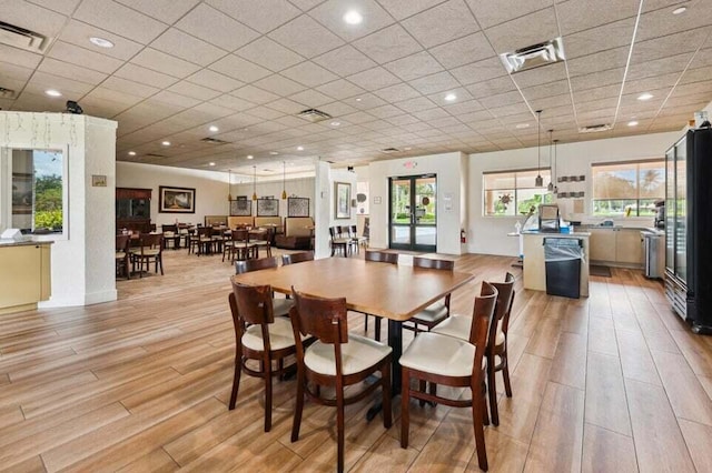 dining space with french doors, light hardwood / wood-style floors, and a drop ceiling