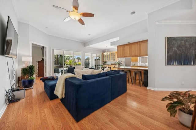 living room featuring ceiling fan with notable chandelier, ornamental molding, and light hardwood / wood-style floors