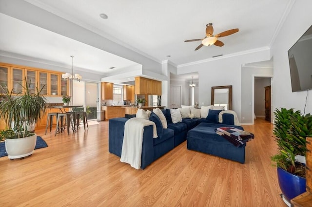 living room featuring ornamental molding, ceiling fan with notable chandelier, and light wood-type flooring