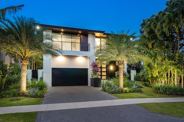 view of front of house featuring a garage, a lawn, and a balcony