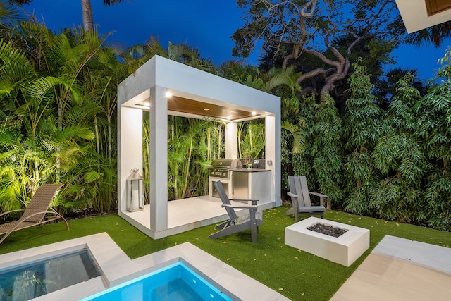 pool at night with a jacuzzi, a fire pit, and a patio area