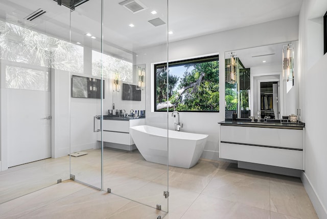 bathroom with a washtub, vanity, and tile floors