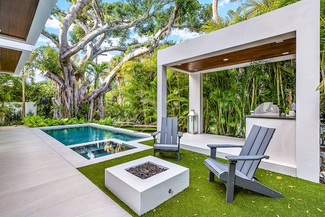 view of pool with a patio area, exterior kitchen, an outdoor fire pit, and grilling area