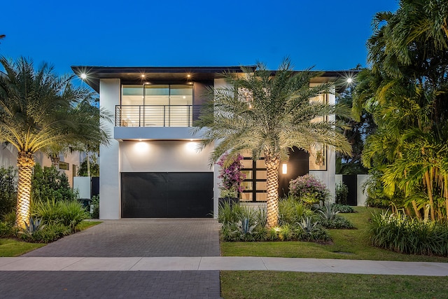 view of front of home with a garage, a lawn, and a balcony